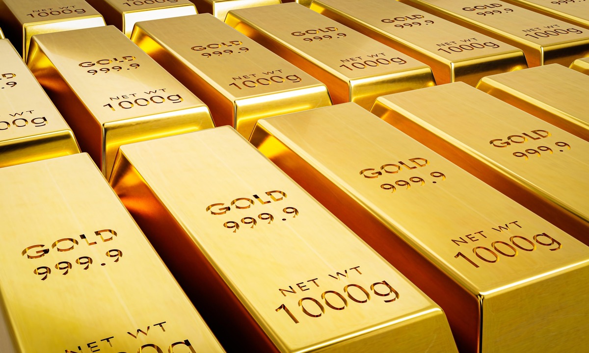 A close-up shot of multiple fine gold bars stacked neatly on top of each other, with one bar in the foreground showing the engraved text "FINE GOLD 999.9". The bars have a smooth, reflective surface, indicating their purity and value.